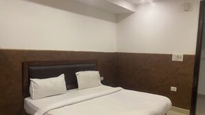 Un lit bien fait, avec une tête de lit en bois, une literie blanche et un mur d’accent de couleur marron.