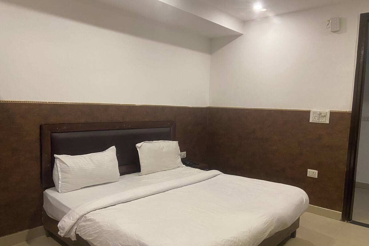 Un lit bien fait, avec une tête de lit en bois, une literie blanche et un mur d’accent de couleur marron.