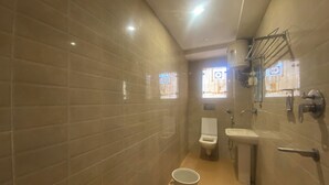 Une petite salle de bain avec des toilettes, un lavabo et un seau.