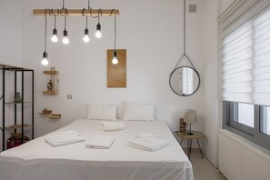 Une chambre à coucher avec un lit, des tables de chevet, un miroir et une fenêtre avec des stores.