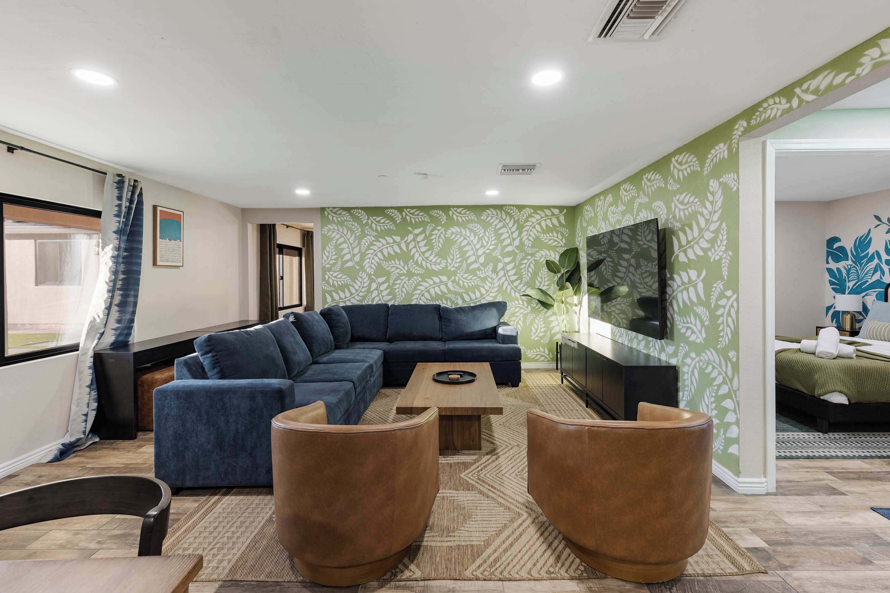 A modern living room with a sectional sofa, a coffee table, and two leather armchairs.