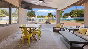 Un patio al aire libre con una mesa y sillas de comedor, un sofá y un ventilador de techo.