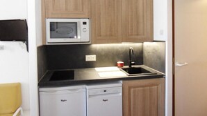 A compact kitchen with wooden cabinets, a microwave, a sink, and a dishwasher. - Ski-in/ski-out & foot of the slopes, 2nd floor, view ski slopes, balcony, tv, ski locker, 27m² (La Plagne)
