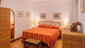 Un dormitorio con una cama de madera, un aparador, un espejo y cuadros en la pared.