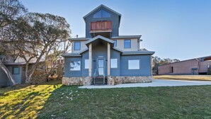A two-story house with a stone foundation, a front porch, and a small upper deck. - The Staggerinn - Dinner Plain (Dinner Plain)