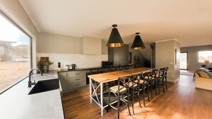 A modern kitchen with a long wooden table, black chairs, and pendant lights. - The Staggerinn - Dinner Plain (Dinner Plain)