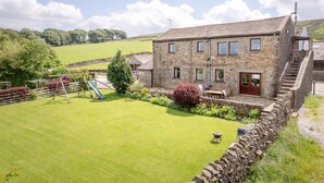 A stone building with a grassy yard, a slide, and a stone wall. - Higher Gills Farm, Stunning Views, 4 bedroom (Clitheroe)