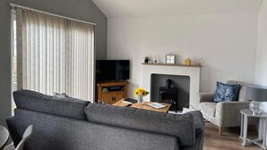 A modern living room with a grey sofa, a wooden coffee table, a fireplace, and a television. - Seaside Escape Chalet in Bridlington South Shore (Bridlington)
