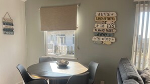 A dining area with a round table, four chairs, and a bowl on the table. There is a window with a view of buildings outside. - Seaside Escape Chalet in Bridlington South Shore (Bridlington)