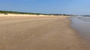 A wide sandy beach with gentle waves, a clear sky, and a distant shoreline with buildings. - Seaside Escape Chalet in Bridlington South Shore (Bridlington)