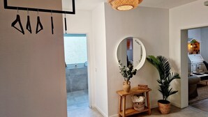 Un intérieur moderne avec une console en bois, un miroir et un luminaire suspendu.