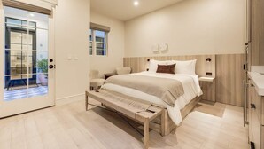 A modern bedroom with a large bed, bedside tables, a bench, and a view of the outside. - Casa De La Vina Studio 5 (Santa Barbara)