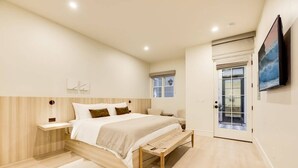 Ein modernes Schlafzimmer mit einem hölzernen Bettgestell, einem Nachttisch, einer Bank und einem großen Fenster.