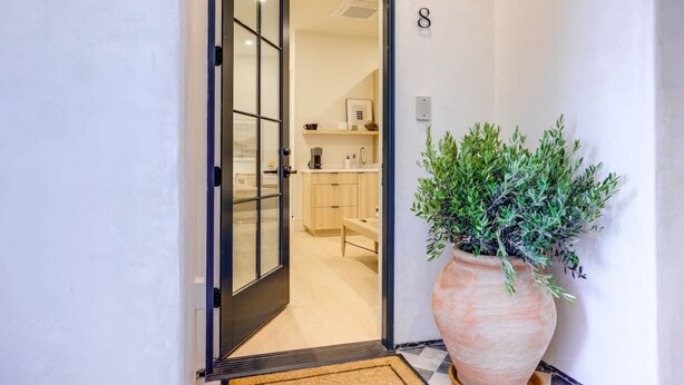 A hallway with a large potted plant, a door with glass panels, and a number '8' on the wall.