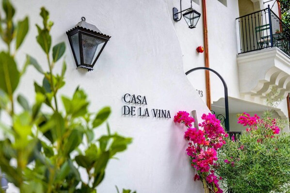 Un edificio blanco con la inscripción "CASA DE LA VINA" y un farol negro.