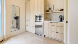 Una cocina moderna con armarios de madera clara, electrodomésticos de acero inoxidable y horno empotrado.