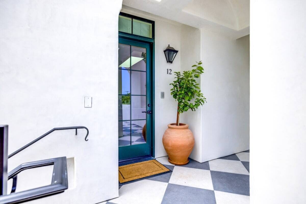 A hallway with a checkered floor, a green door, and a potted plant.