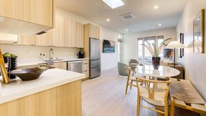 Una cocina moderna con armarios de madera, una isla grande y una zona de comedor con una mesa redonda y sillas.