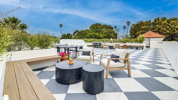 Un patio al aire libre con piso a cuadros, mobiliario exterior y vistas del paisaje circundante.