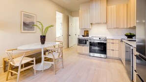 Una cocina moderna con armarios de madera, horno integrado y un comedor con una mesa redonda y sillas.