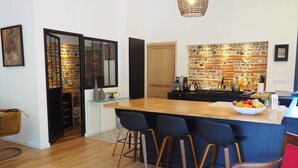 A modern kitchen with a central island, bar stools, and a red chair. - Chambre D'hôtes En Apar-té en Fond de Jardin Calme Relaxation Piscine (Toulouse)