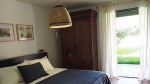 A bedroom with a bed, a hanging light fixture, a wooden wardrobe, and a view of the outdoors. - Chambre D'hôtes En Apar-té en Fond de Jardin Calme Relaxation Piscine (Toulouse)