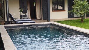 A swimming pool with lounge chairs and a small table. - Chambre D'hôtes En Apar-té en Fond de Jardin Calme Relaxation Piscine (Toulouse)