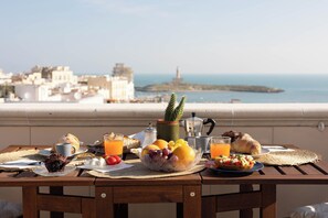 Una tavola imbandita per la colazione, con diversi cibi e vista su una città costiera.