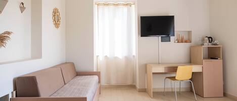 A modern bedroom with a bed, a desk, a chair, a TV, and a window with curtains.