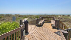 Een houten terras met uitzicht op het strand en de oceaan.