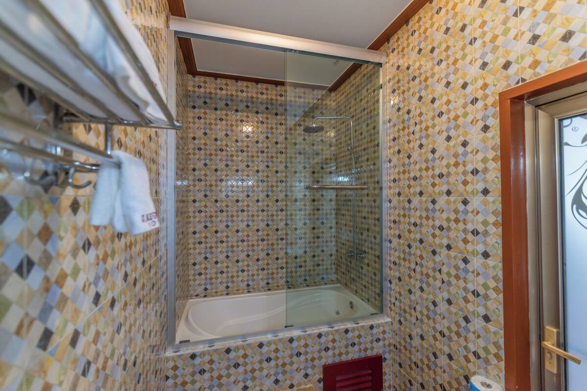A bathroom with a glass-enclosed shower, a bathtub, and a tiled wall.