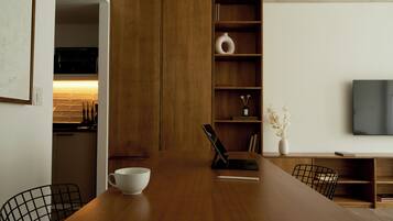 Una cocina moderna con armarios de madera, horno empotrado y un comedor con mesa de madera, sillas y un tazón blanco.