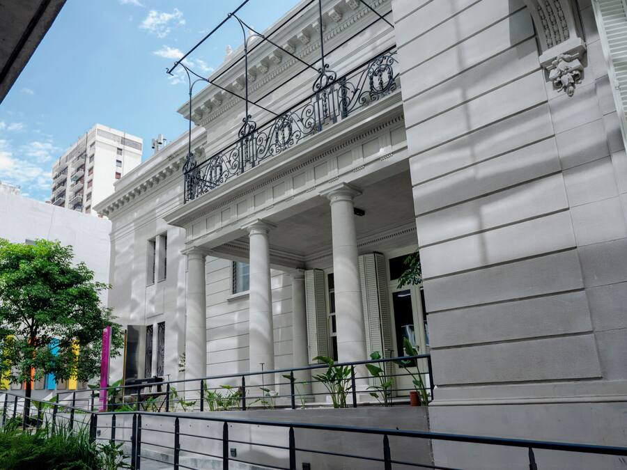Un edificio classico con colonne bianche e un balcone dotato di elaborate ringhiere in metallo.