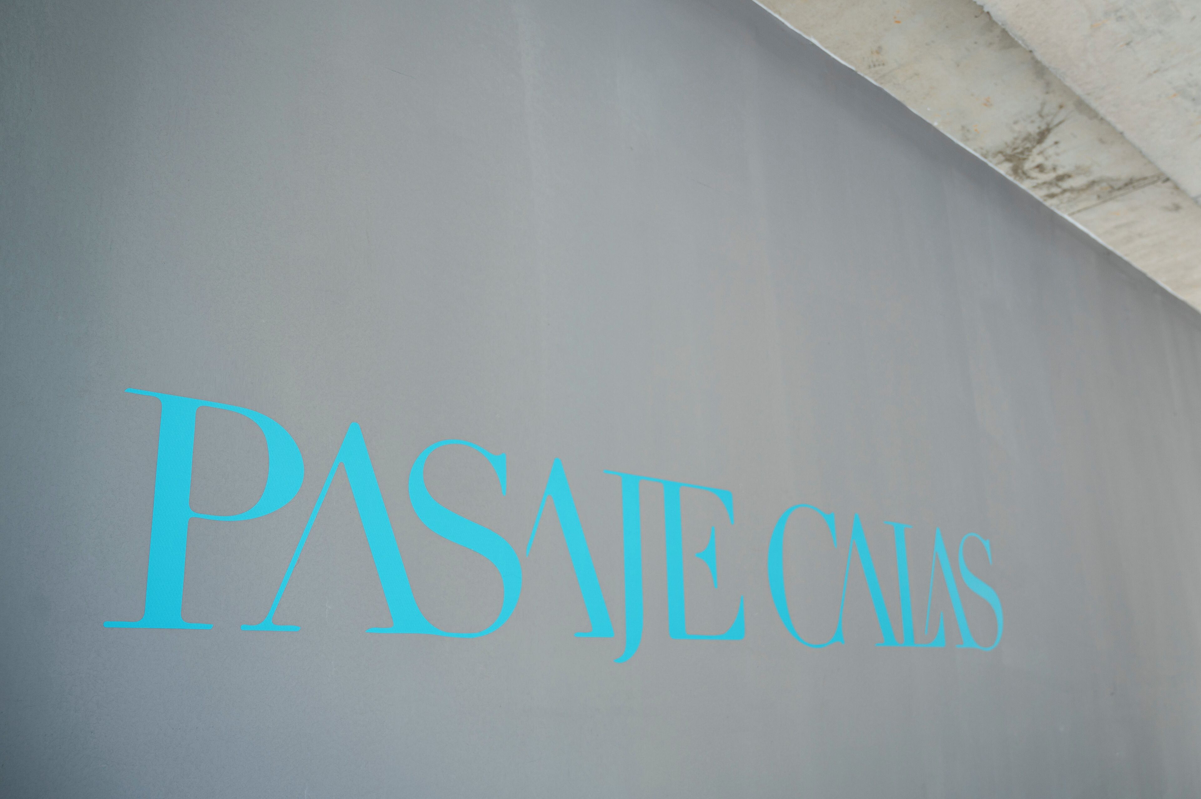 A sign with the text "PASAJES CALAS" in blue letters on a grey background.