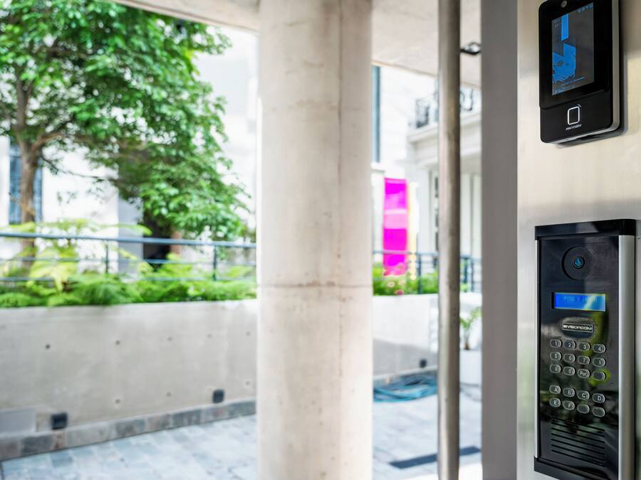 A modern building entrance with a security keypad and a digital display.