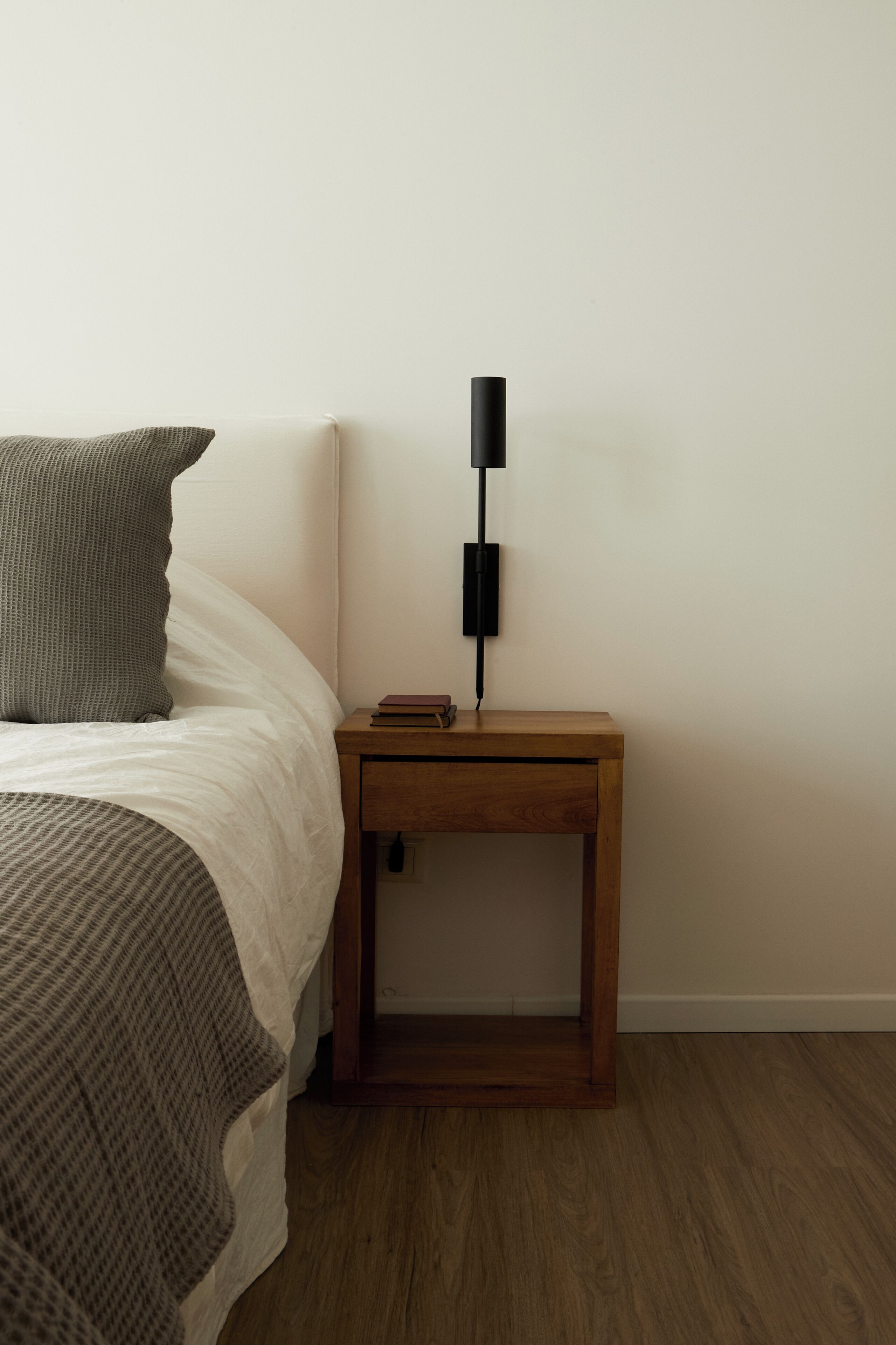 A bedroom with a bed, a bedside table with a lamp, and a nightstand.