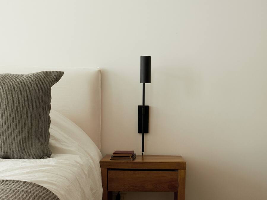 A bedroom with a bed, a bedside table with a lamp, and a nightstand.