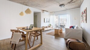 Un espace de vie moderne comprenant une table à manger en bois, un canapé et un pouf en osier.