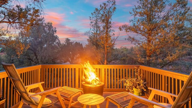 Una terraza con un pozo de fuego, sillas de madera y una mesa.
