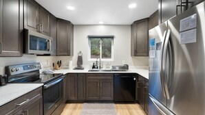 Una cocina moderna con armarios de madera oscura, electrodomésticos de acero inoxidable y una ventana que proporciona luz natural.
