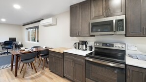 Una cocina moderna con armarios oscuros, un microondas, un horno y una cafetera.