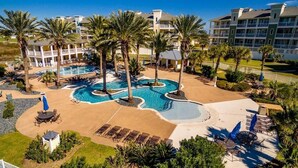 Un resort con piscina central, palmeras y un edificio con balcones.