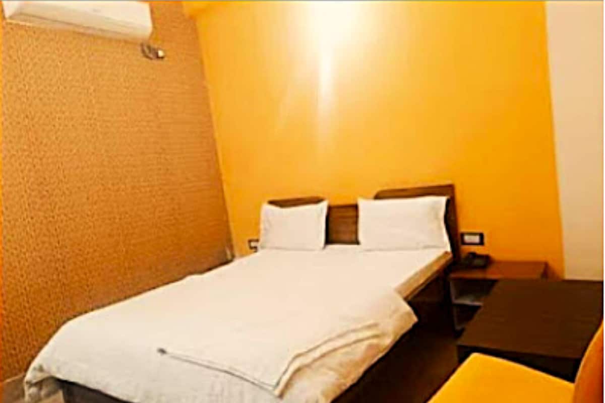 A single bed with white bedding in a room with orange walls.