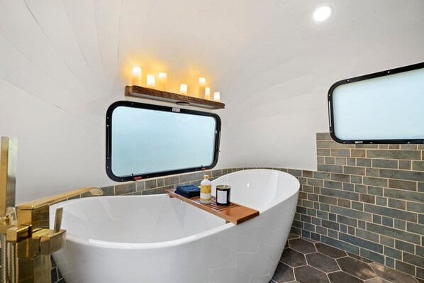 A modern bathroom with a freestanding bathtub, a window, and a mirror.