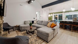 A modern living room with a grey sectional sofa, a round coffee table, and a stone accent wall. - Carolina Wildwood in Fletcher (Fletcher)