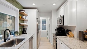 A modern kitchen with white cabinets, granite countertops, and stainless steel appliances. - Carolina Wildwood in Fletcher (Fletcher)