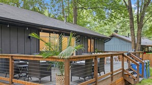 A wooden deck with outdoor seating, a staircase, and a building with a dark facade. - Carolina Wildwood in Fletcher (Fletcher)