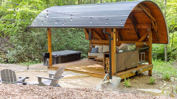 A rustic wooden cabin with a covered porch, outdoor seating, and a hot tub. - Creekside Fern in Pisgah Forest (Pisgah Forest)