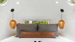 A bedroom with a bed, two hanging lamps, and a view of greenery through a window. - Silver Fern in Pisgah Forest (Pisgah Forest)