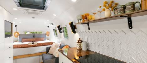 A compact living space with a bed, sofa, kitchenette, and a window with a view.